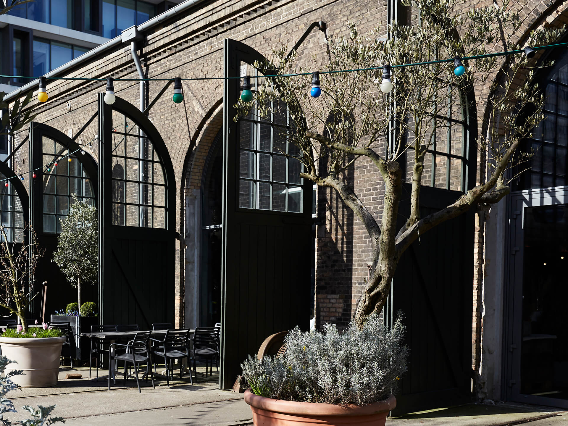 Hele togvogne kunne i gamle dage køre igennem de høje døre i Centralværkstedernes bygninger. I dag åbner de ud til den solrige gård, hvor man også kan nyde en kop kaffe fra caféen, der ligger i Boogieværkstedet, som bygningen tættest på banegården bliver kaldt.